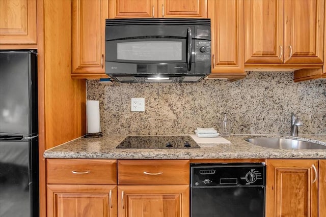 kitchen featuring sink, tasteful backsplash, light stone counters, and black appliances