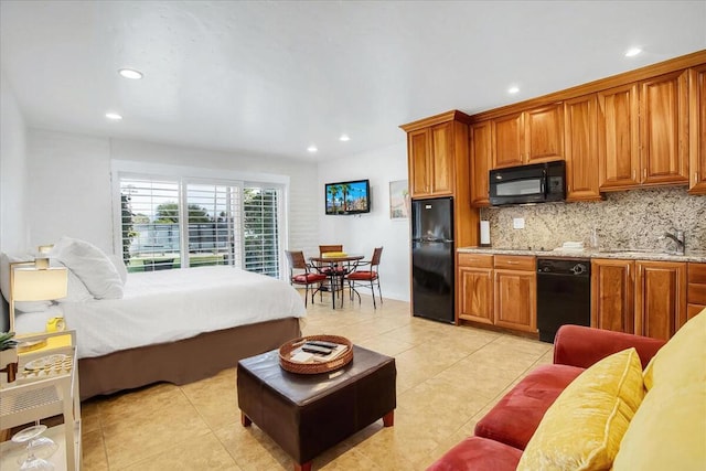 bedroom featuring light tile patterned flooring, black refrigerator, and sink