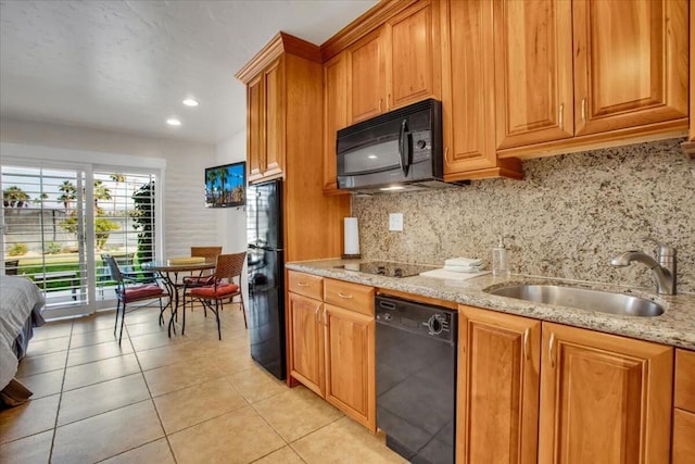 kitchen with light stone countertops, black appliances, decorative backsplash, sink, and light tile patterned floors