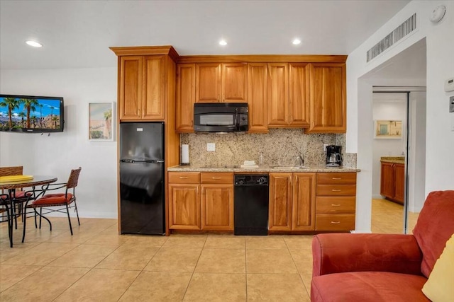 kitchen featuring light stone countertops, light tile patterned floors, backsplash, and black appliances