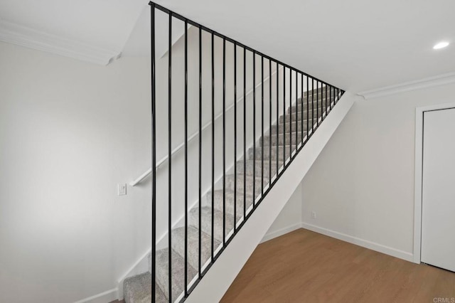 stairway featuring wood-type flooring and ornamental molding