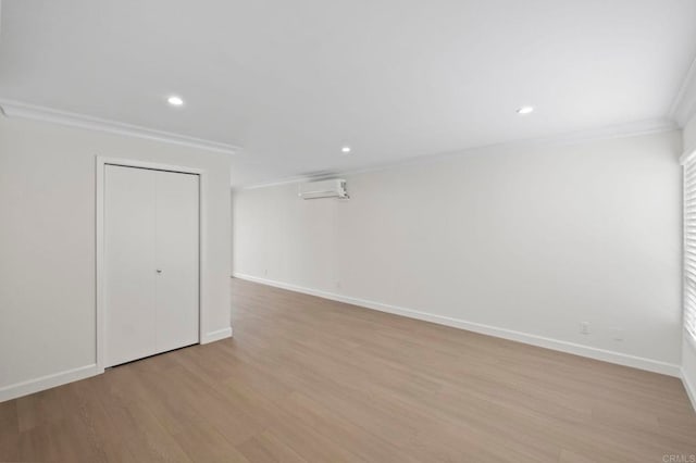 interior space with light wood-type flooring, an AC wall unit, and crown molding