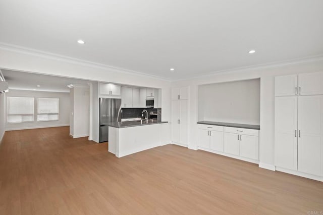 unfurnished living room featuring ornamental molding, light hardwood / wood-style flooring, and sink