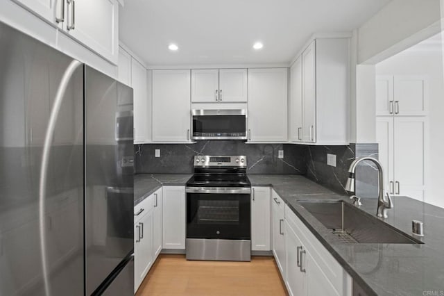 kitchen featuring decorative backsplash, appliances with stainless steel finishes, sink, and white cabinetry