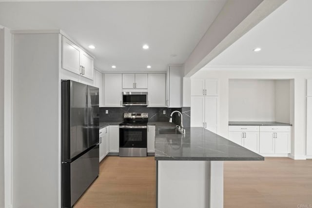 kitchen featuring decorative backsplash, sink, white cabinetry, light wood-type flooring, and stainless steel appliances