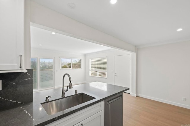 kitchen with white cabinets, dark stone counters, light hardwood / wood-style floors, sink, and stainless steel dishwasher