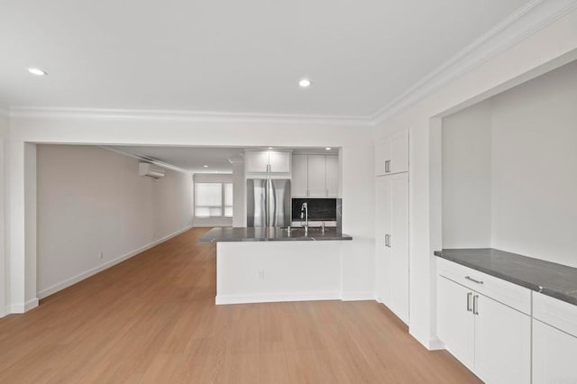 kitchen with white cabinetry, kitchen peninsula, stainless steel fridge, decorative backsplash, and light hardwood / wood-style flooring