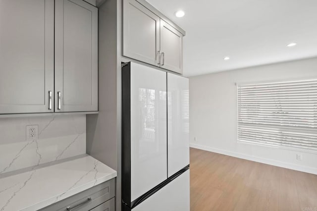 kitchen with white fridge, light stone countertops, tasteful backsplash, and gray cabinets