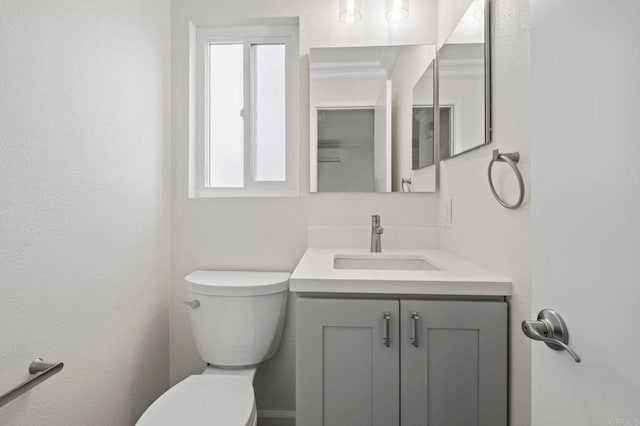 bathroom featuring toilet, vanity, and ornamental molding