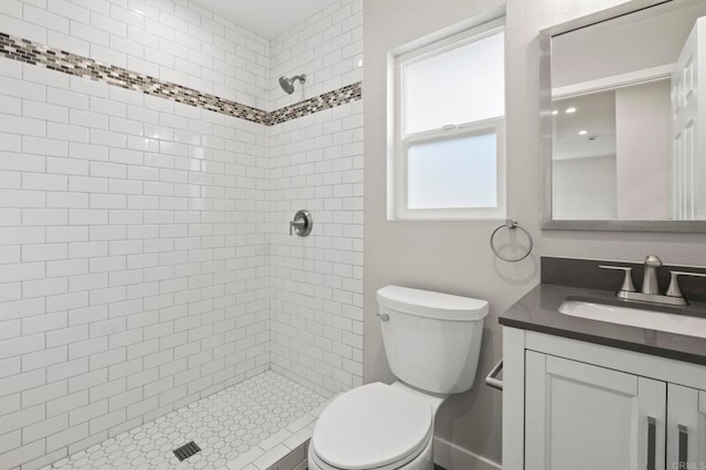 bathroom featuring toilet, tiled shower, and vanity