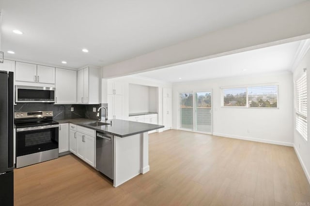 kitchen with decorative backsplash, white cabinetry, appliances with stainless steel finishes, and kitchen peninsula