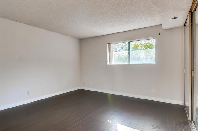 unfurnished room with dark hardwood / wood-style floors and a textured ceiling