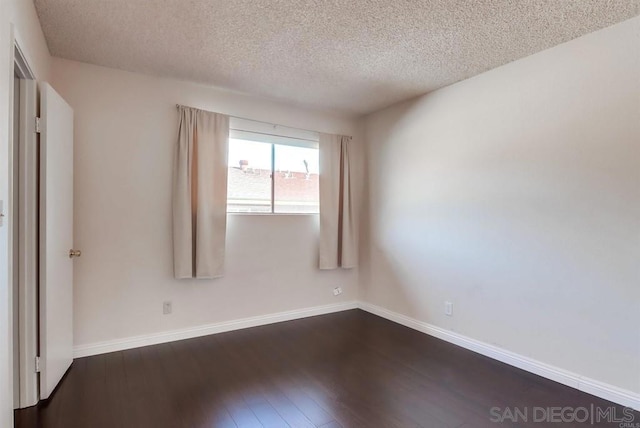 spare room featuring dark hardwood / wood-style floors and a textured ceiling