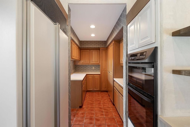 kitchen with built in fridge, light tile patterned flooring, backsplash, and double oven