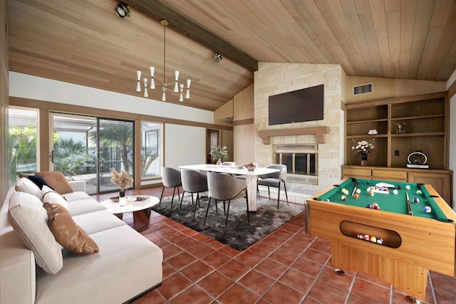 recreation room featuring a stone fireplace, lofted ceiling with beams, dark tile patterned floors, wood ceiling, and an inviting chandelier