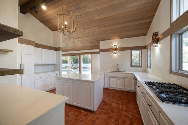 kitchen featuring sink, white cabinetry, stainless steel gas cooktop, a kitchen island, and wooden ceiling