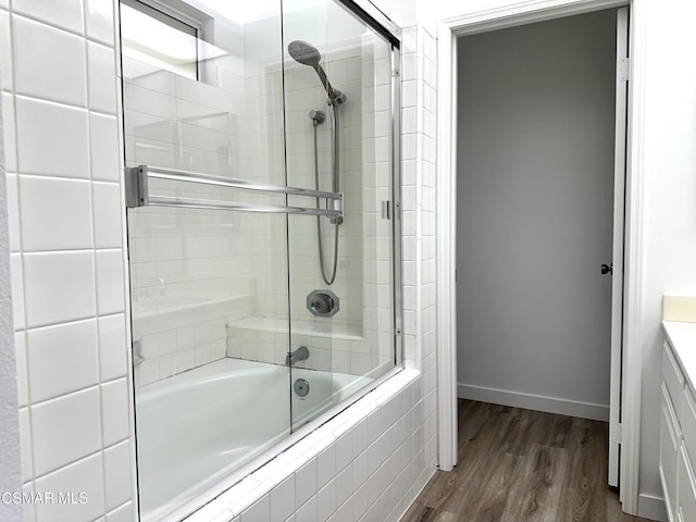 bathroom with enclosed tub / shower combo, wood-type flooring, and vanity