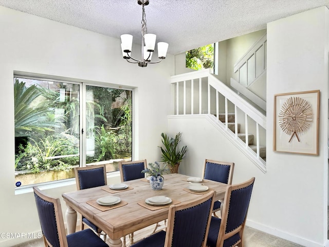 dining room featuring a textured ceiling, carpet, and a chandelier