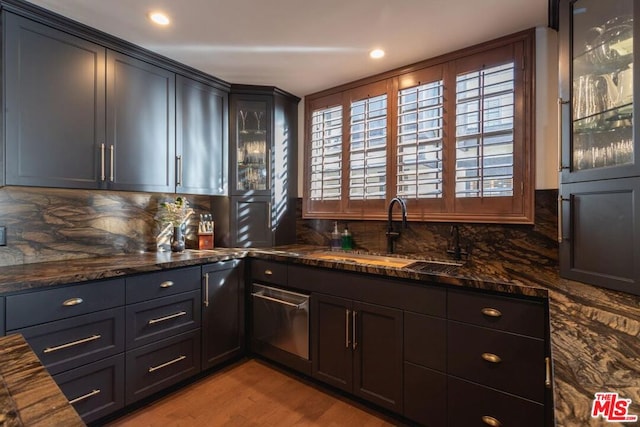 kitchen with backsplash, dark stone counters, sink, and light hardwood / wood-style floors