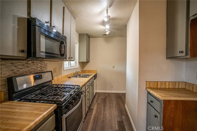 kitchen featuring gas range, sink, dark hardwood / wood-style flooring, and track lighting