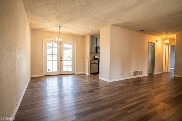 unfurnished living room featuring french doors, dark hardwood / wood-style floors, a chandelier, and a textured ceiling