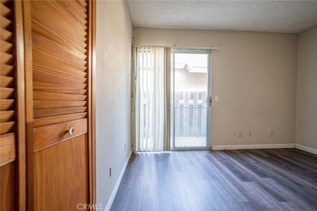 unfurnished room featuring a textured ceiling and dark hardwood / wood-style flooring