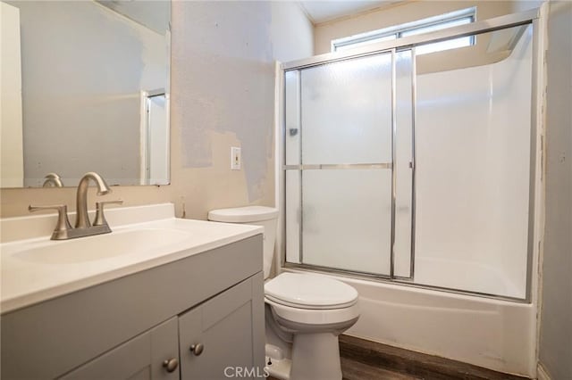 full bathroom featuring hardwood / wood-style flooring, enclosed tub / shower combo, vanity, and toilet