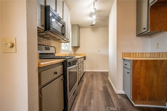 kitchen featuring rail lighting, stainless steel gas stove, dark hardwood / wood-style floors, and tasteful backsplash