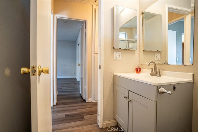 bathroom with a textured ceiling, wood-type flooring, and vanity