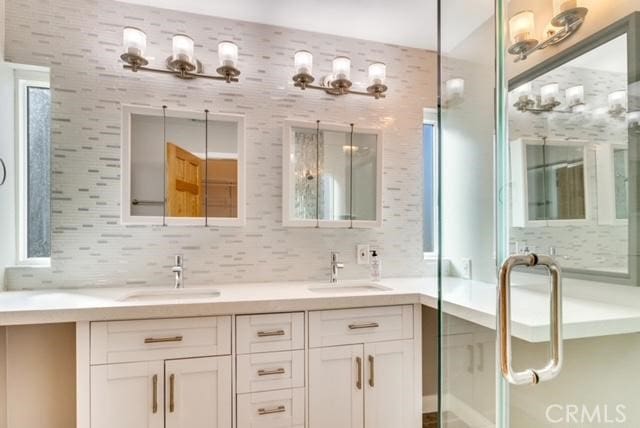 bathroom with an enclosed shower, vanity, and backsplash