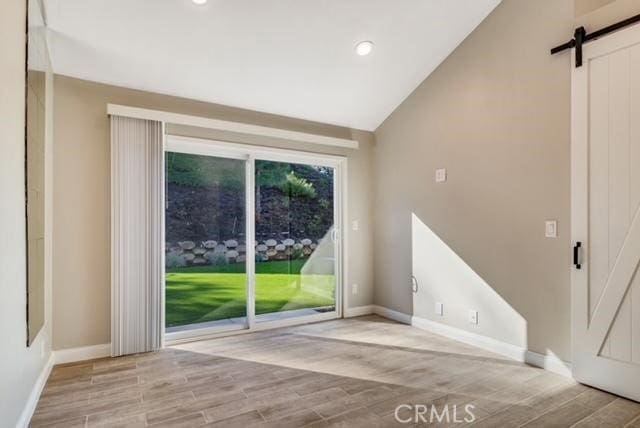 interior space featuring a barn door and vaulted ceiling