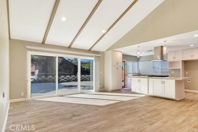 kitchen with decorative light fixtures, extractor fan, light hardwood / wood-style floors, beamed ceiling, and white cabinets