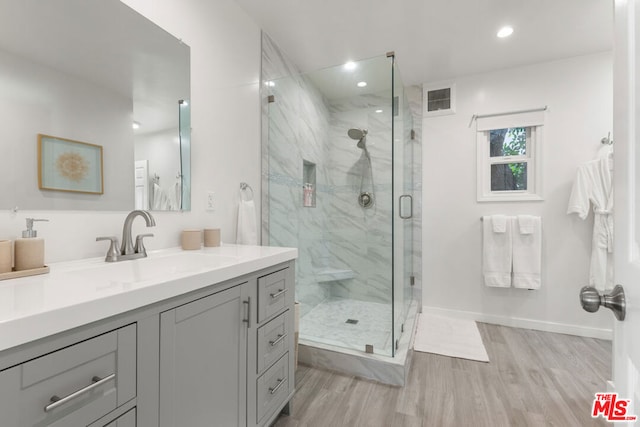 bathroom with hardwood / wood-style floors, an enclosed shower, and vanity