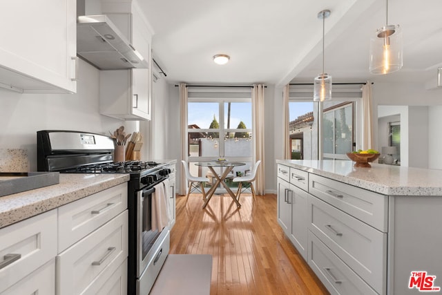 kitchen with white cabinetry, wall chimney range hood, light hardwood / wood-style floors, hanging light fixtures, and stainless steel range with gas stovetop