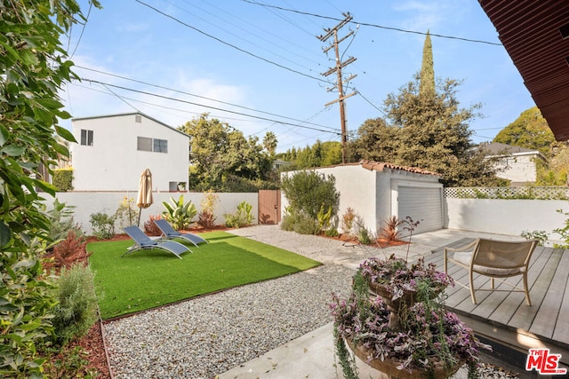 view of yard with a garage, a wooden deck, and an outdoor structure