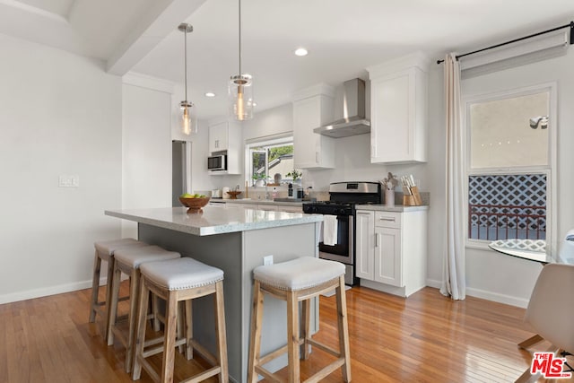 kitchen with white cabinetry, stainless steel appliances, pendant lighting, a kitchen island, and wall chimney exhaust hood