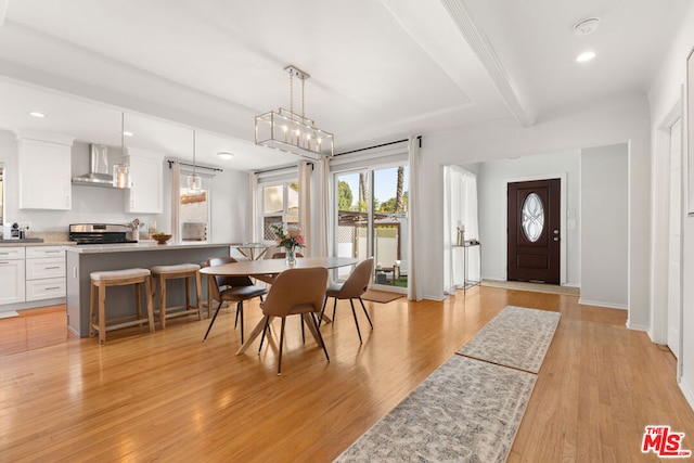 dining room with beam ceiling and light wood-type flooring