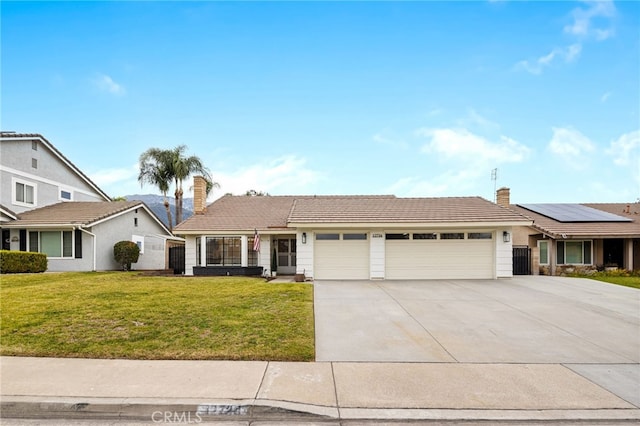 view of front of home with a garage, a front yard, and solar panels