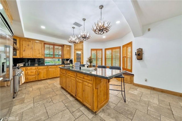 kitchen featuring a kitchen bar, an island with sink, backsplash, decorative light fixtures, and a chandelier