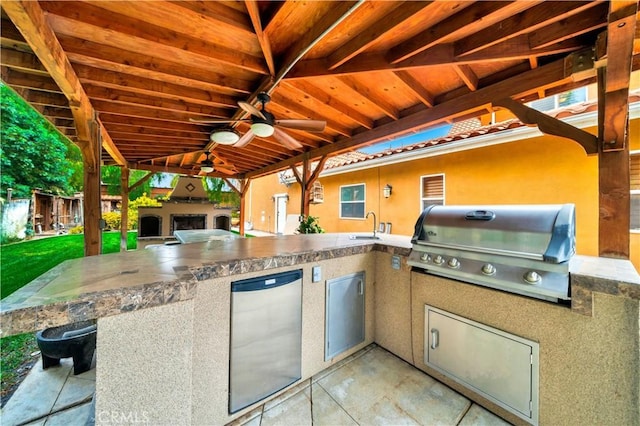 view of patio with ceiling fan, an outdoor kitchen, a fireplace, and grilling area