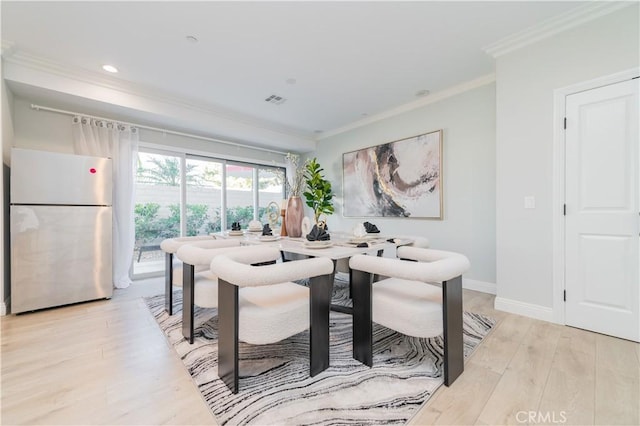 dining room featuring ornamental molding, visible vents, light wood-style flooring, and baseboards