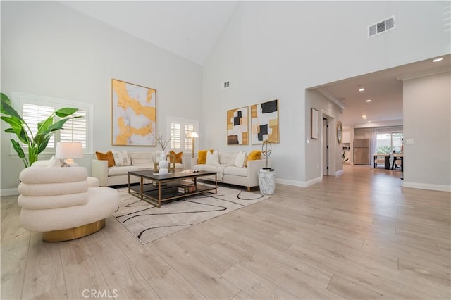 living room featuring a wealth of natural light, visible vents, baseboards, and wood finished floors