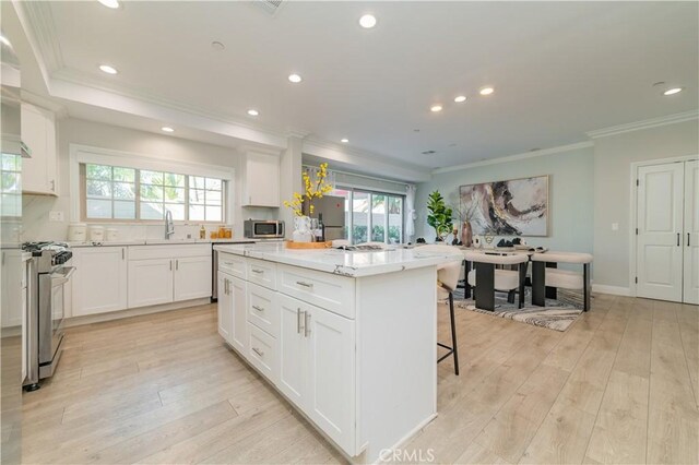 kitchen with appliances with stainless steel finishes, a center island, sink, and white cabinets