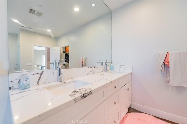 bathroom featuring double vanity, a sink, visible vents, and baseboards