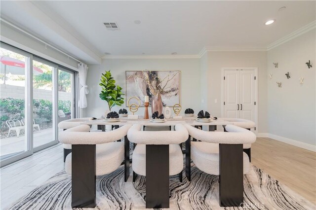 dining room with crown molding and light hardwood / wood-style flooring