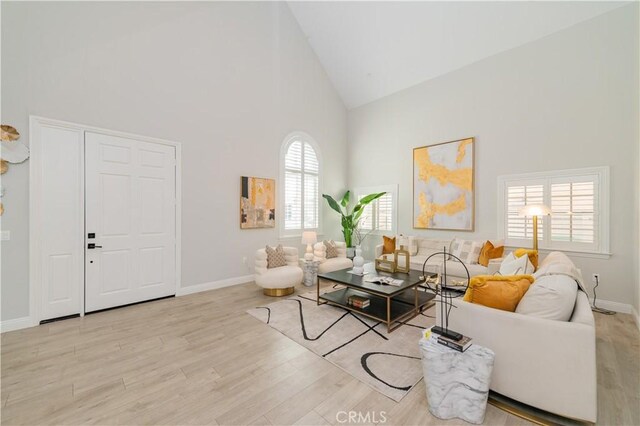 living room with high vaulted ceiling and light hardwood / wood-style flooring