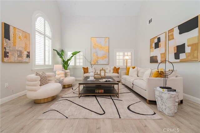 living room with light wood-type flooring and high vaulted ceiling