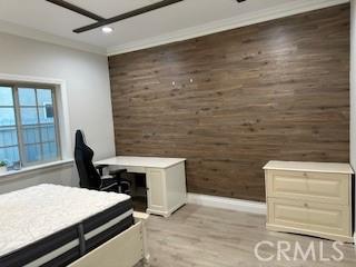 bedroom featuring crown molding, ceiling fan, wood finished floors, and wooden walls