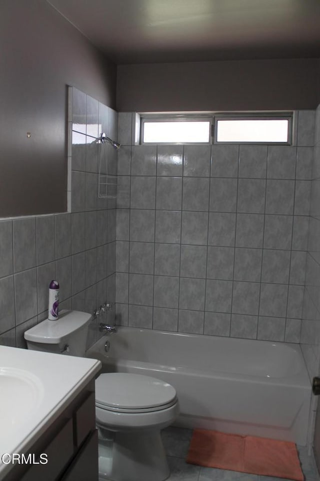 full bathroom featuring a healthy amount of sunlight, tile walls, vanity, and tiled shower / bath combo