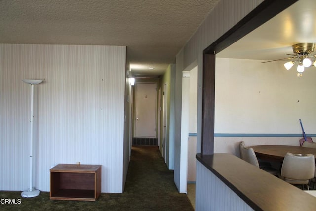 corridor featuring a textured ceiling and dark colored carpet